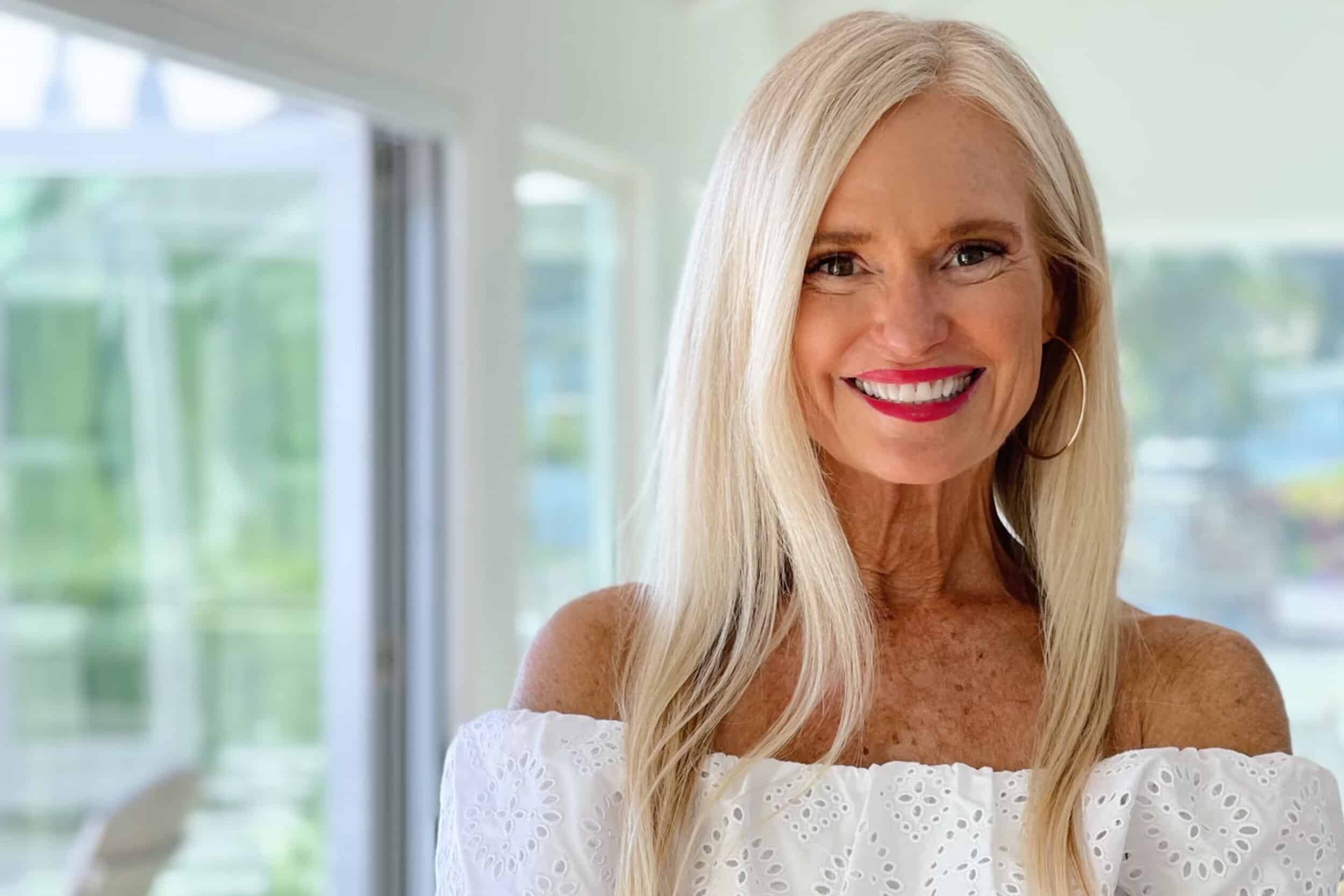 Kym Showers smiling confidently in a stylish white off-shoulder top