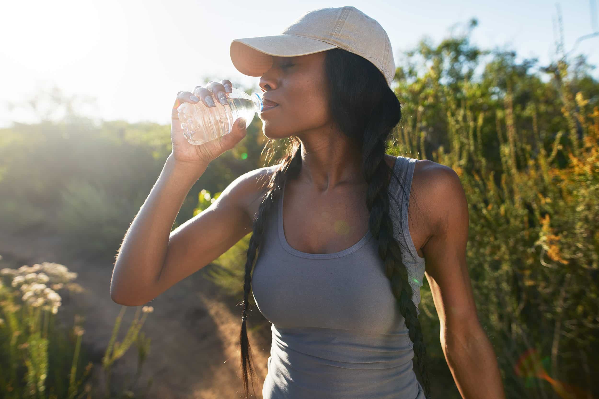 A woman looking refreshed and joyful as she hydrates during her run