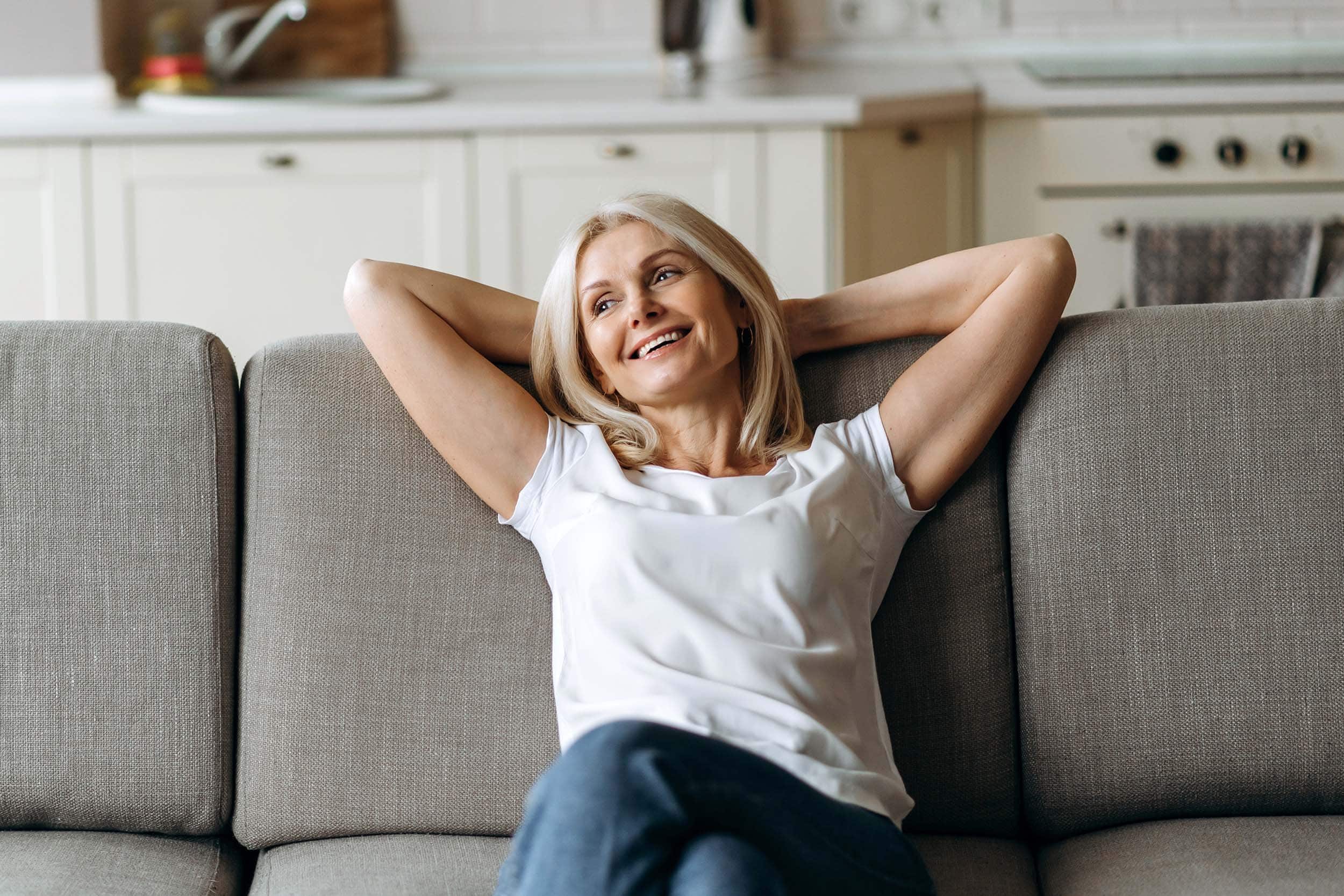 happy and content middle aged woman sitting on a sofa