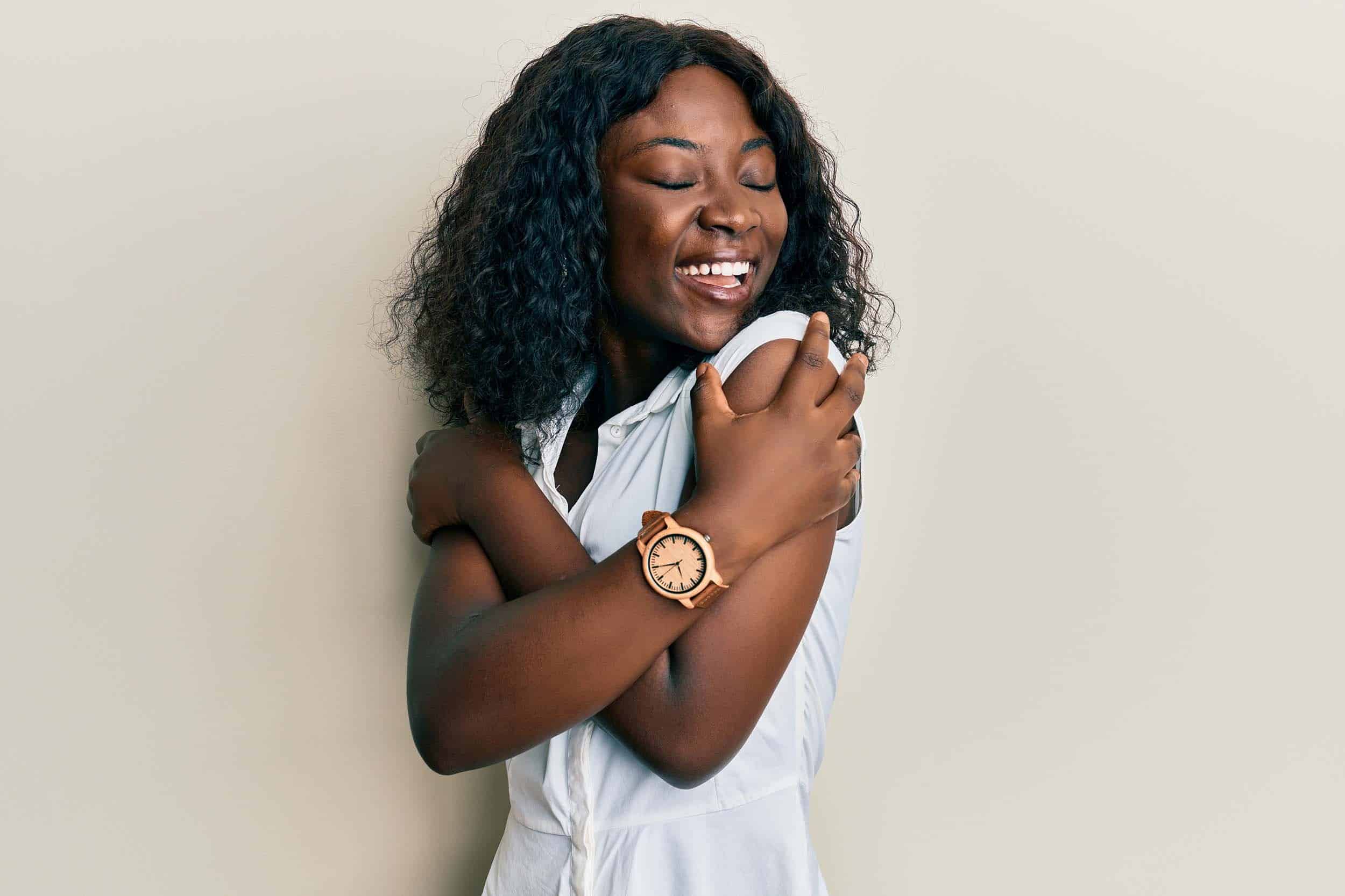 woman in her 40s smiling while embracing herself