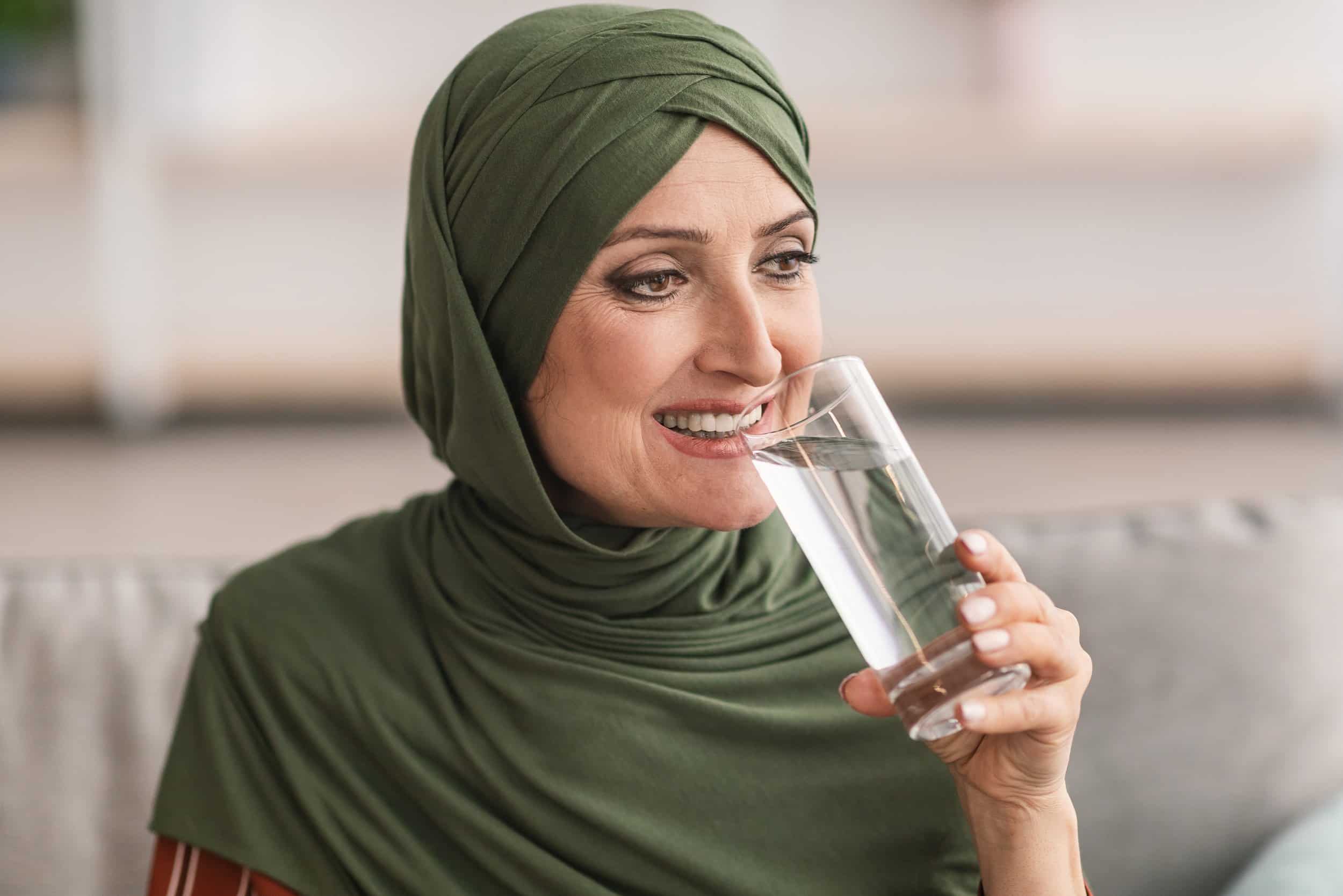 A muslim woman happily drinks water