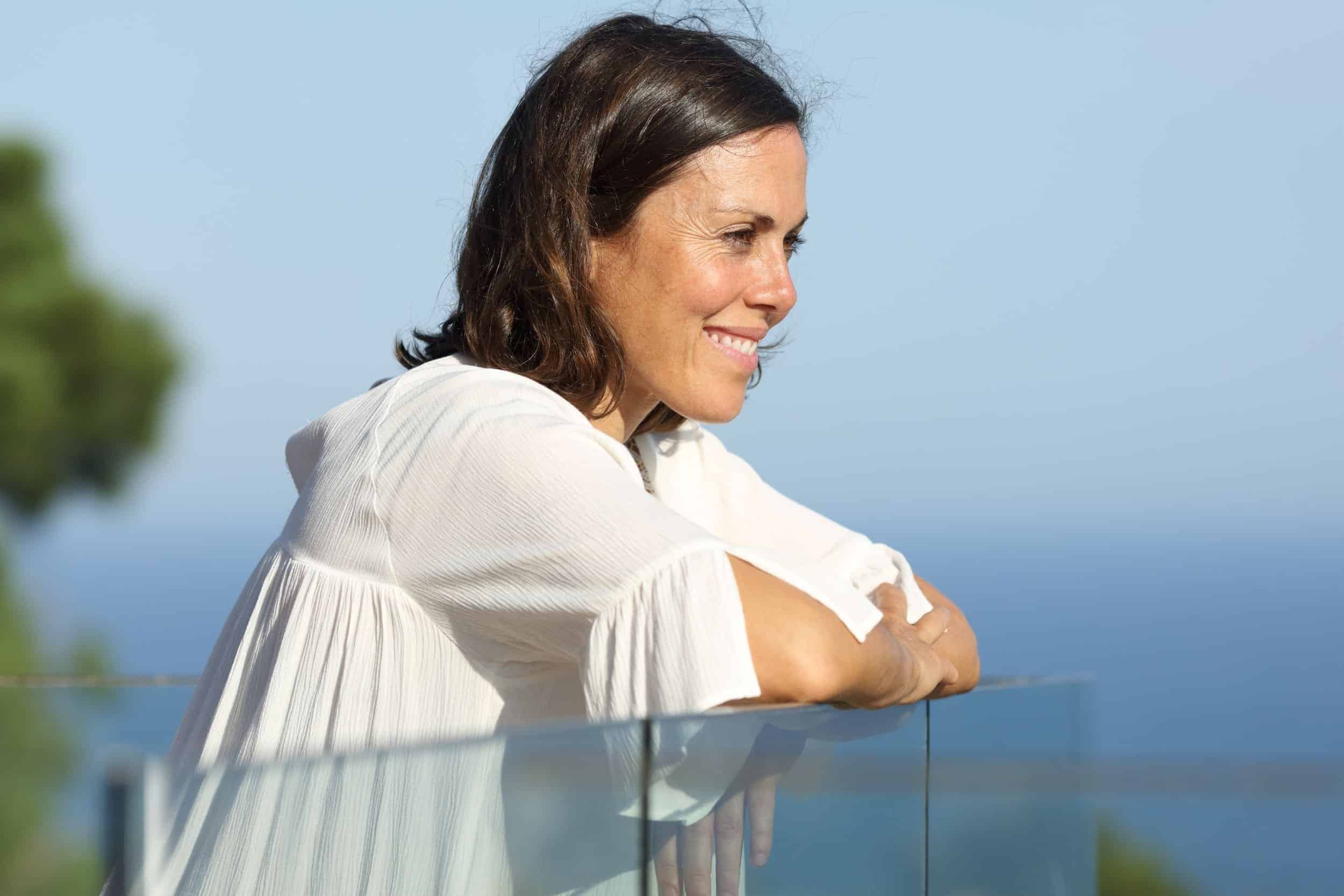 woman in her 50s looking at the sea and smiling