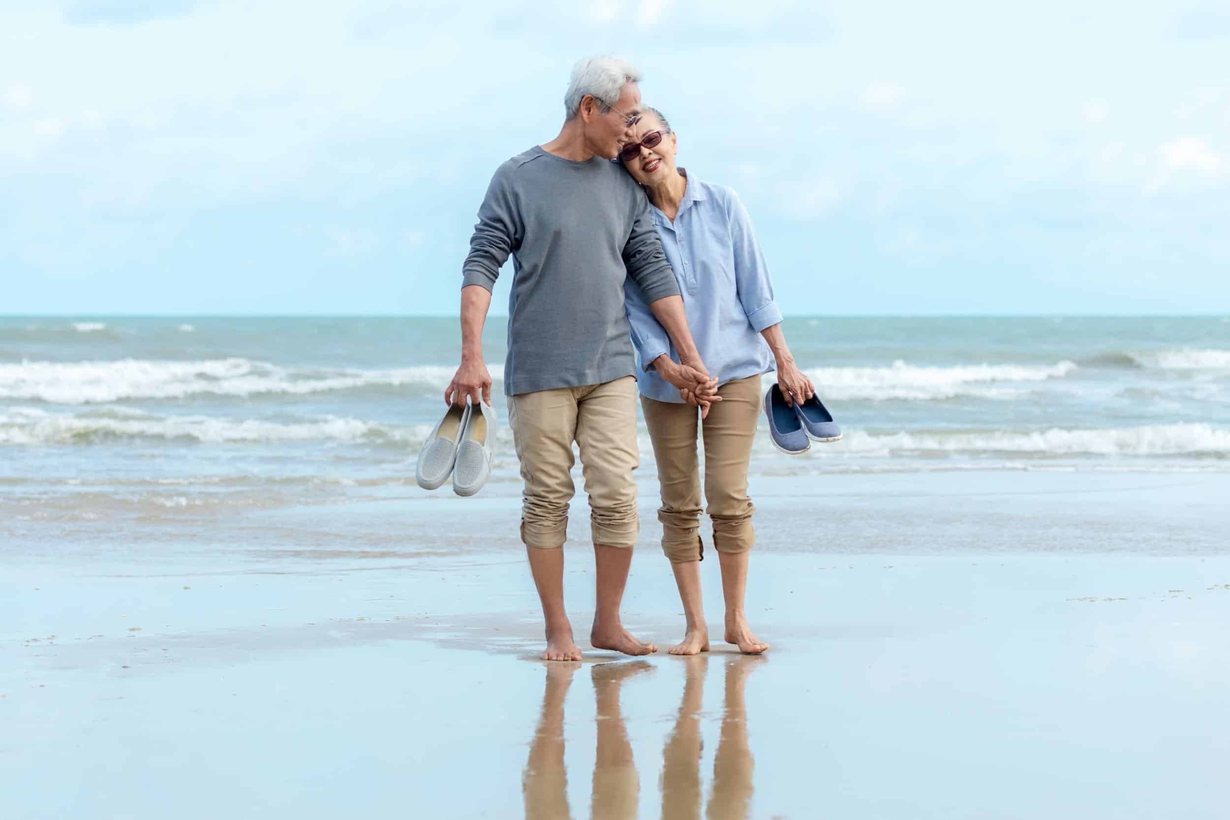 couple in their 60s walking lovingly at the beach