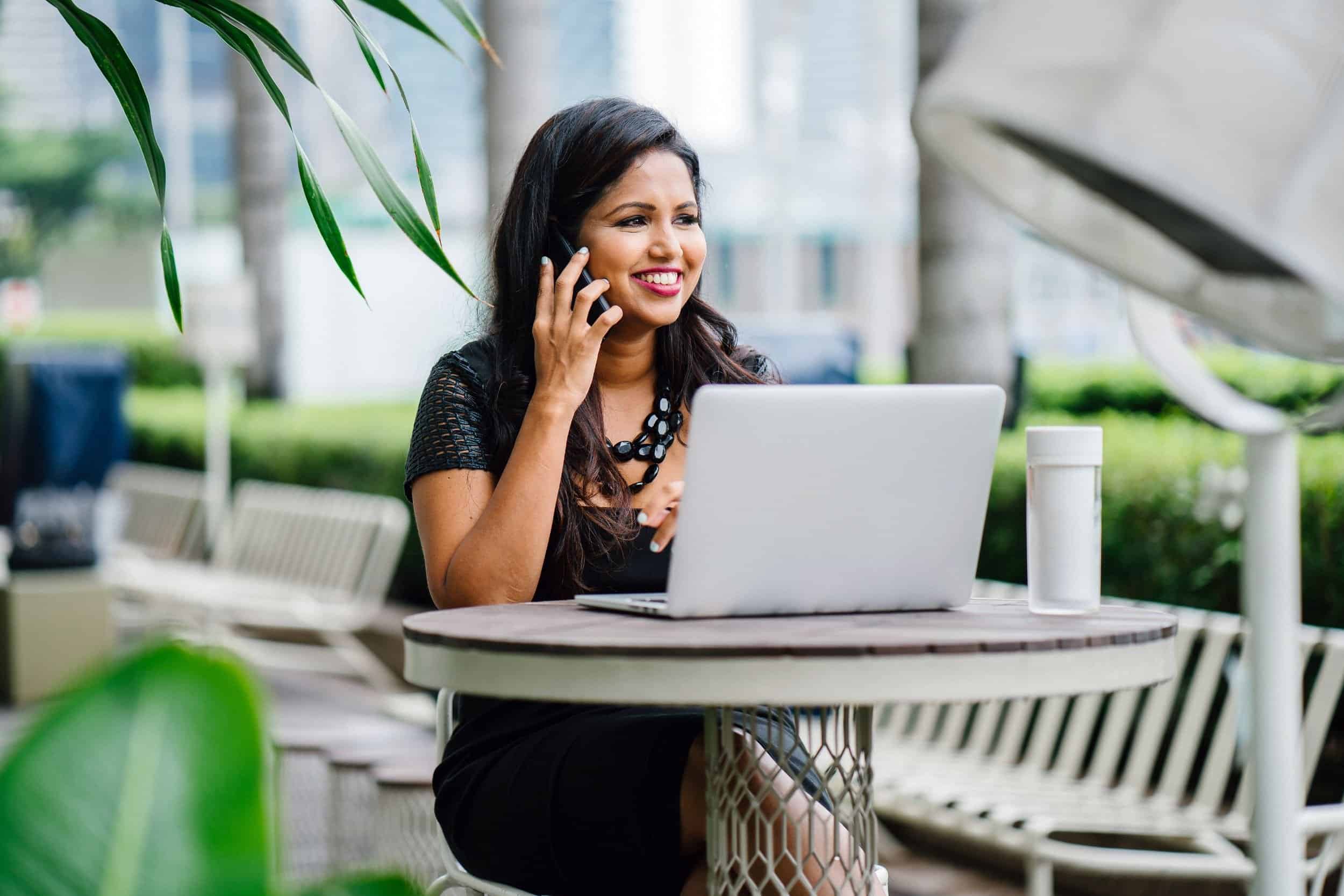 woman in her 40s smiling while talking to someone in her phone