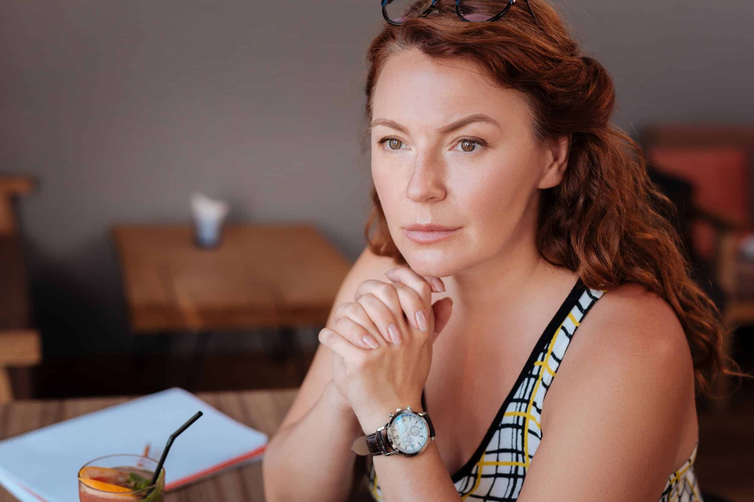 woman in her 40s focused on wondering resting her hands in her chin