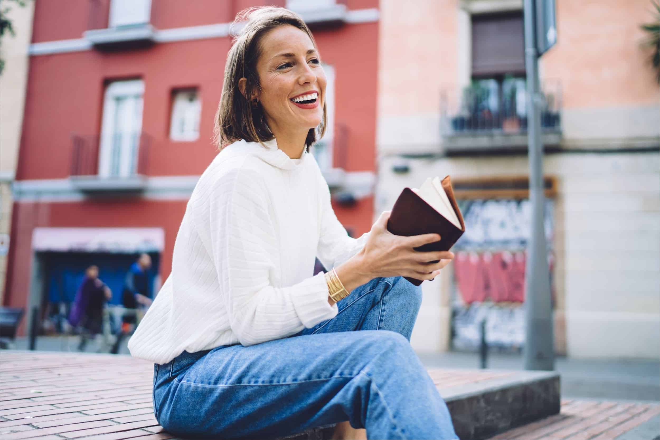 woman in her 40s gives a wide smile while holding her notebook