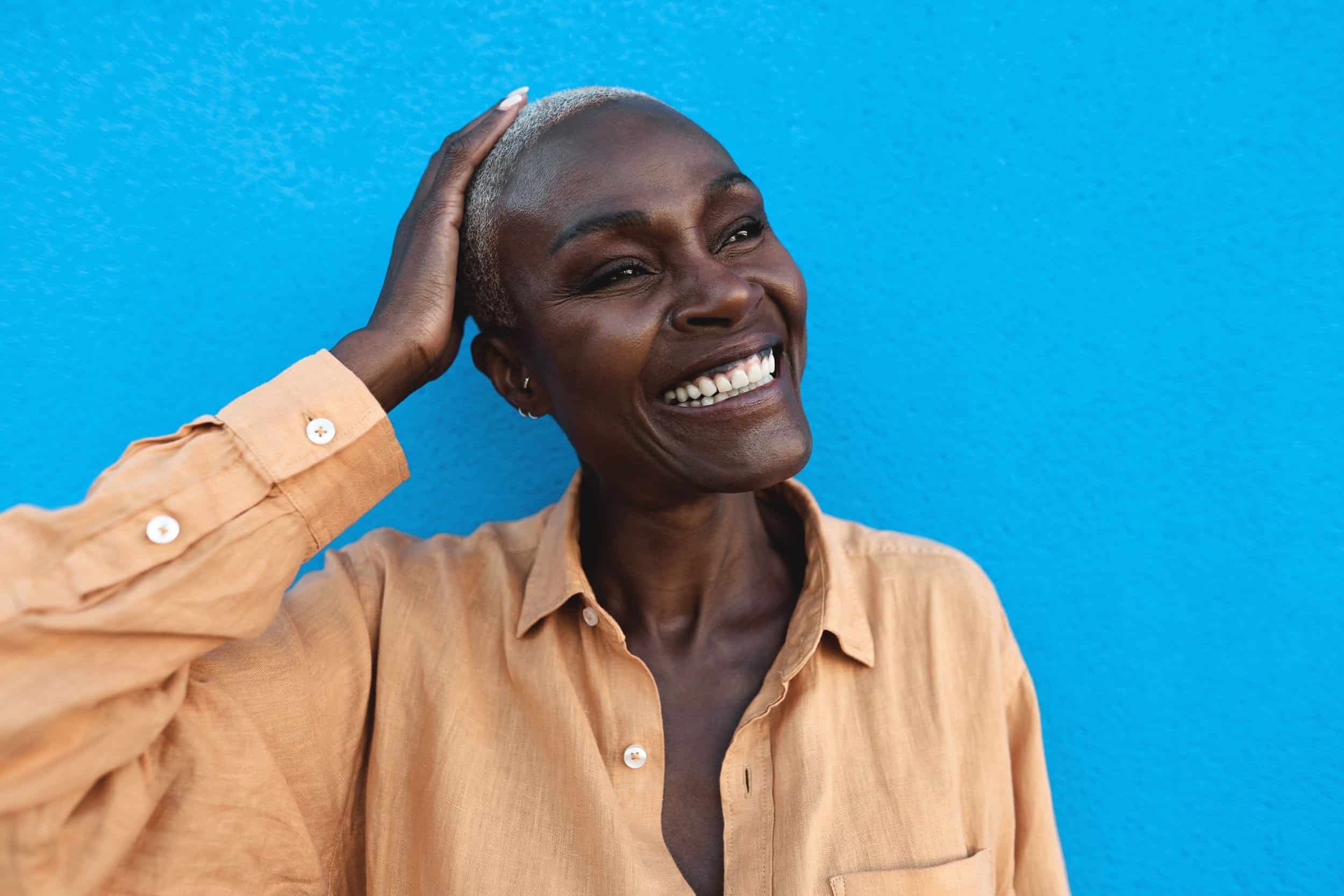 woman in her 40s smiling brightly while looking at her side