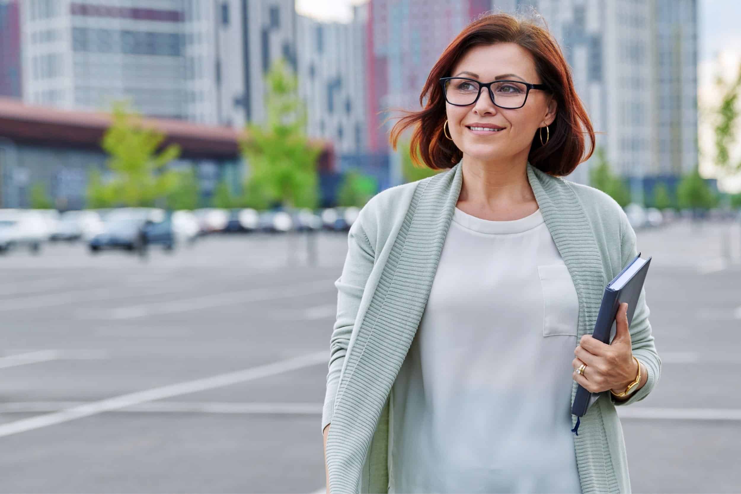 woman in her 40s walking in the city looking at the buildings