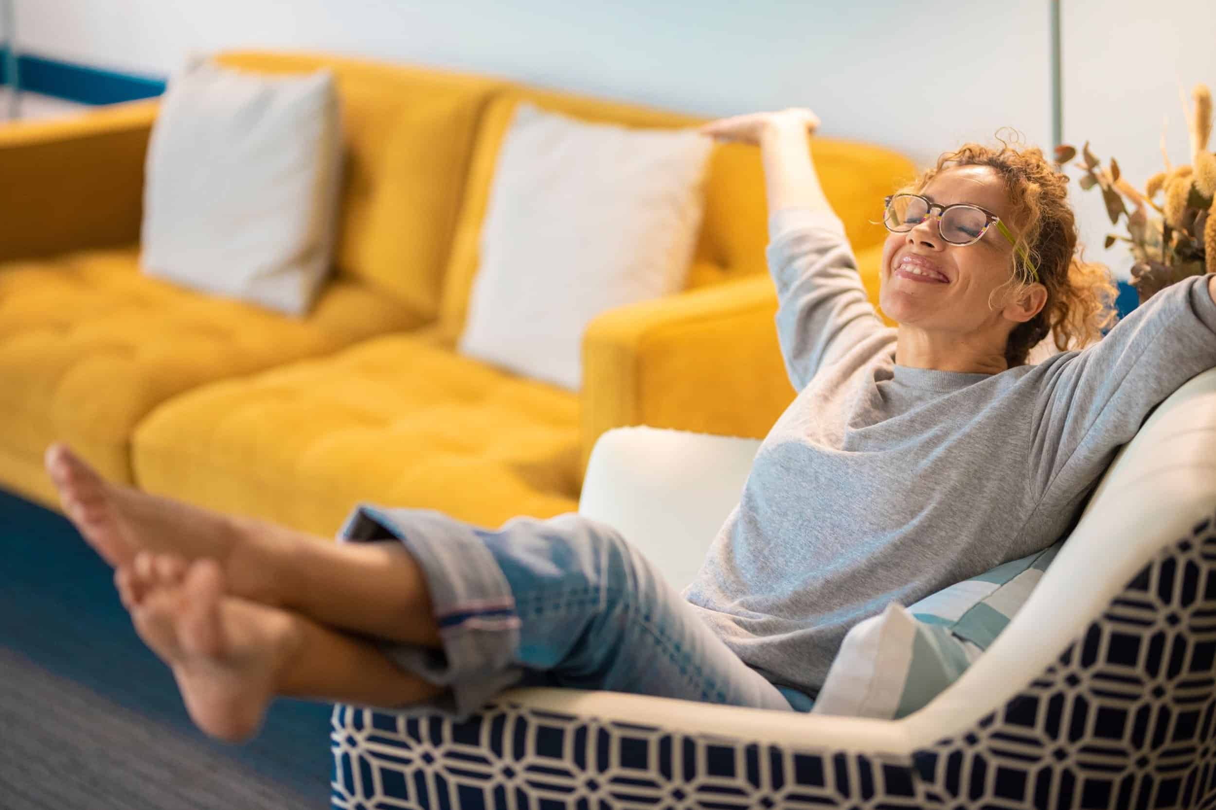 woman in her 40s happily resting in her sofa