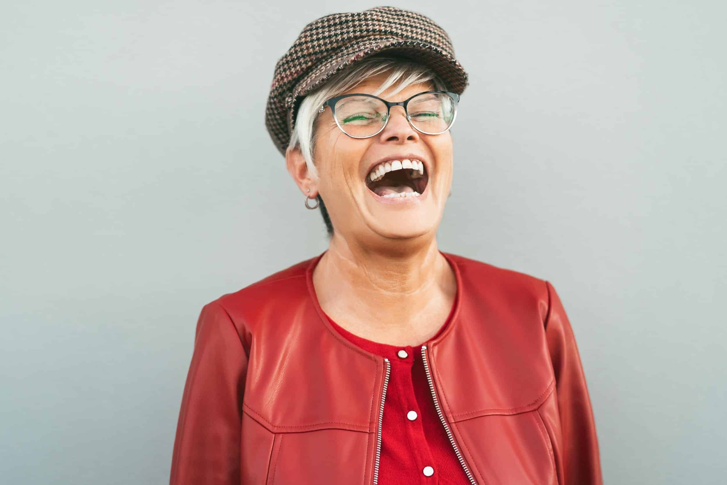 woman in her 40s smiling widely wearing her red leather jacket