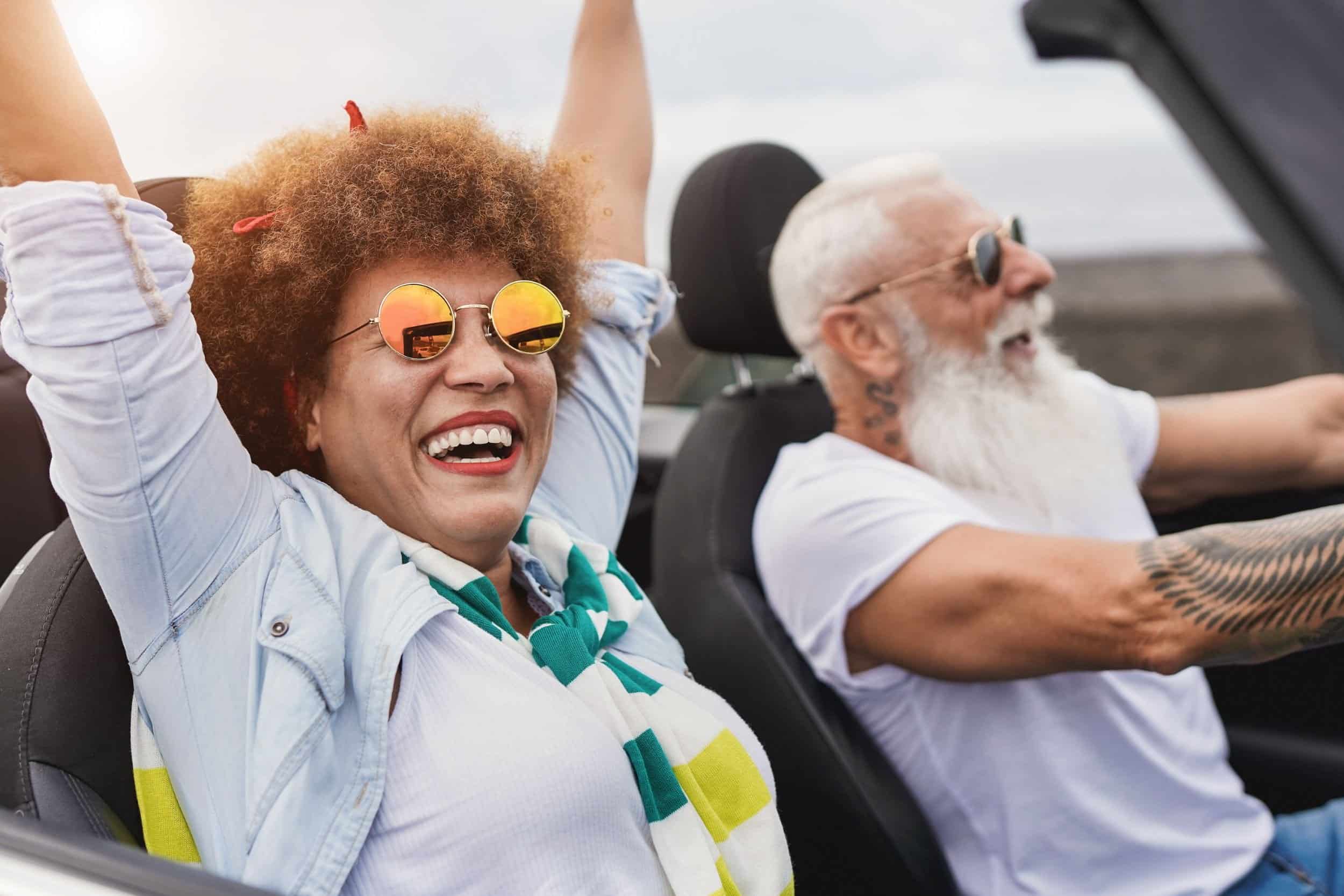 woman having fun raising her hands up in the air while in the passenger seat of a car