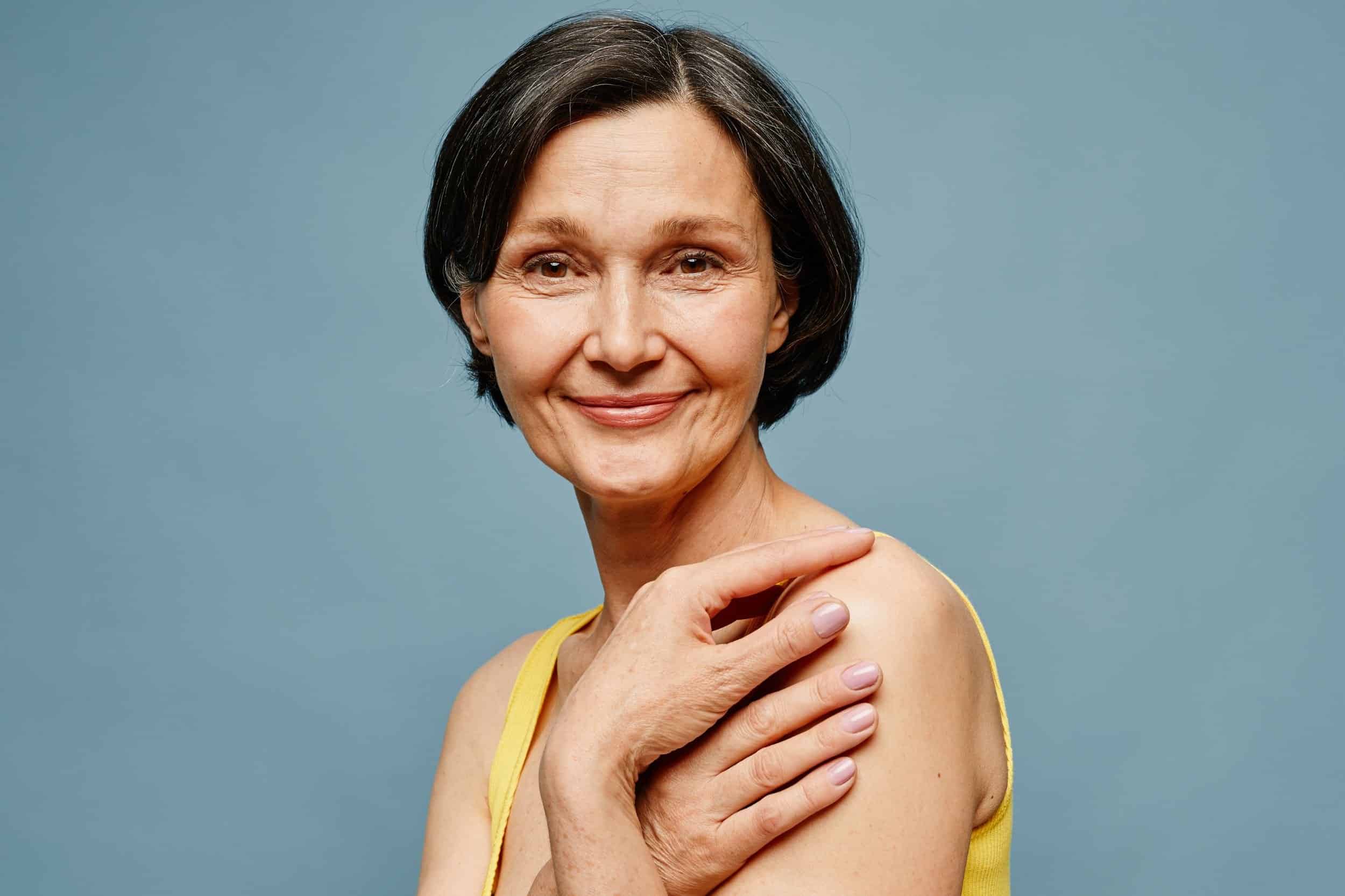 woman in her 50s smiling beautifully wearing a yellow top