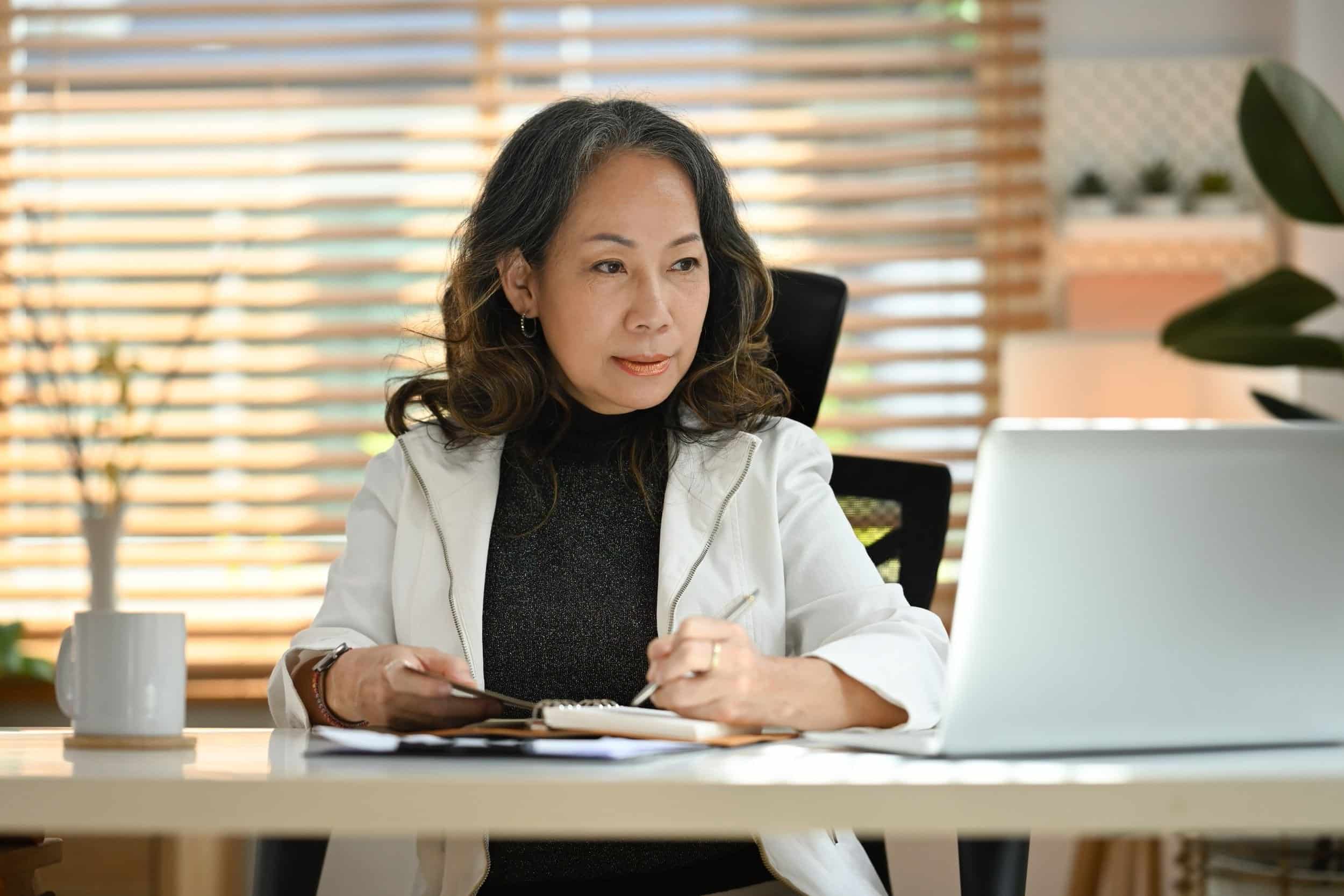 sophisticated woman jotting down notes focused on what she is doing