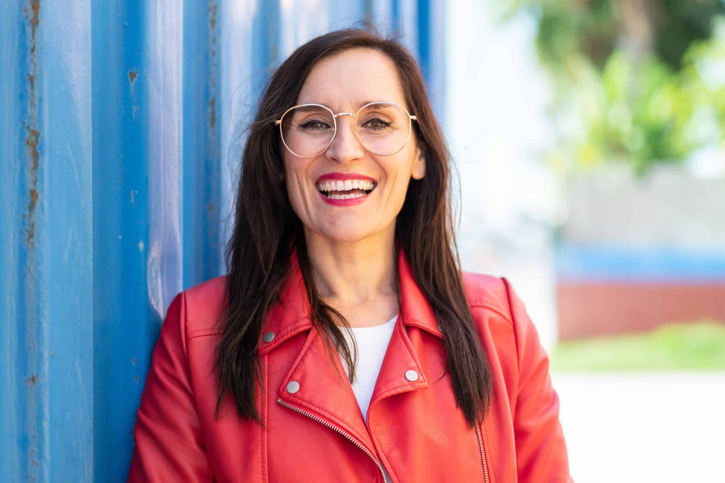 woman in her 50s smiling brightly wearing a red leather jacket