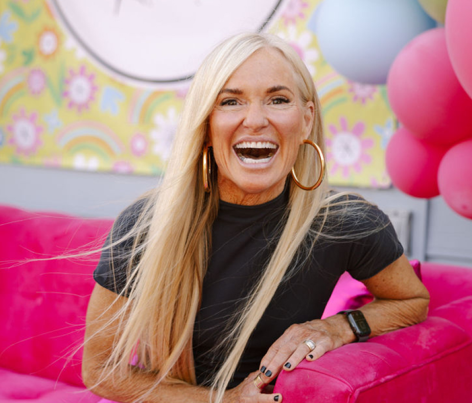 Kym Showers smiling on a pink couch